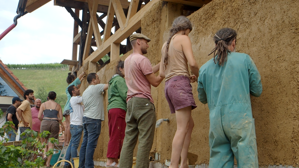 Participants apply a natural clay plaster to a straw bale wall during a hands-on building workshop.