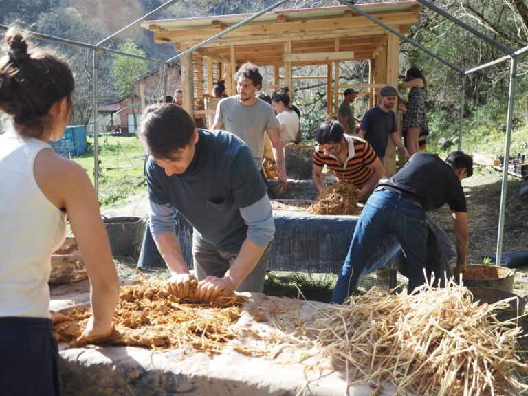 Participants work together with clay and straw during a hands-on natural building workshop.