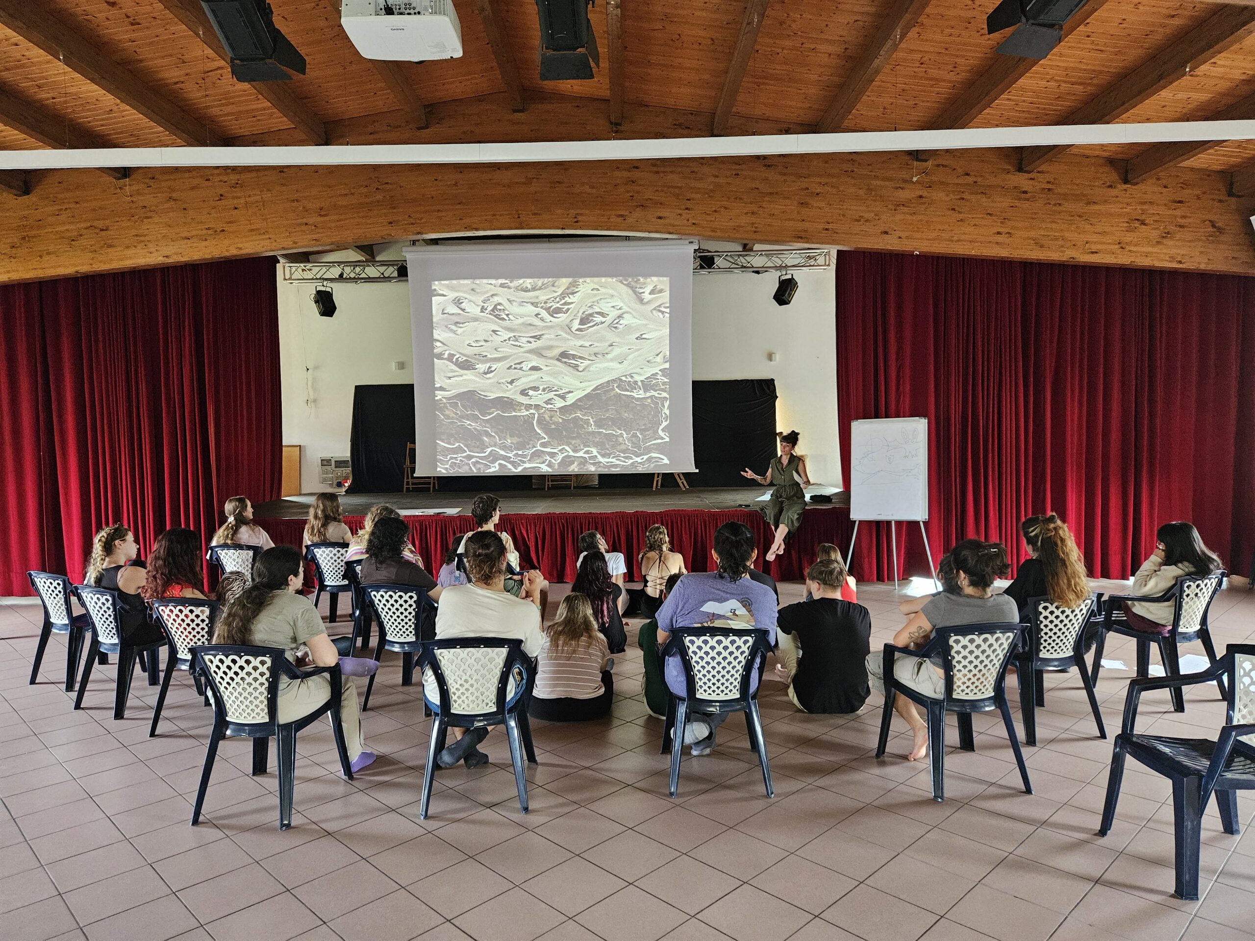Young people sitting on the floor during a participatory documentary filmmaking workshop in Valchiusella, Italy.