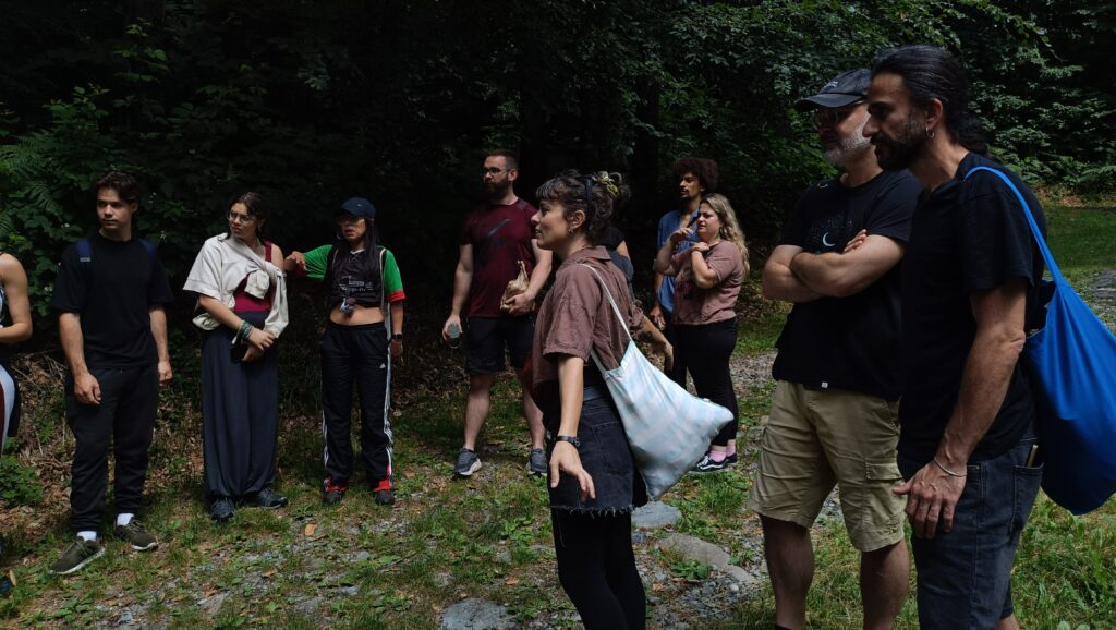 A facilitator leads a group discussion with young people outdoors in a forest in Valchiusella, Italy.